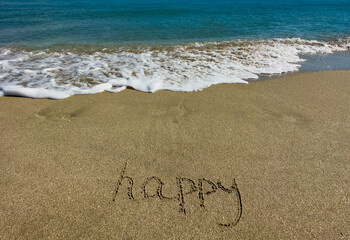 Happy is written on the sand. Message in the sand. Soft focus. 