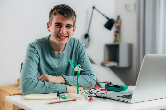 Teenage boy is proud of his wind generator model, look at the camera