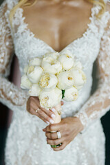 Wedding bouquet in bride's hands with white peonies