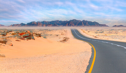 Fototapeta na wymiar Beautiful empty asphalt dirt road in desert plain with mountains in background - Namibia, Africa