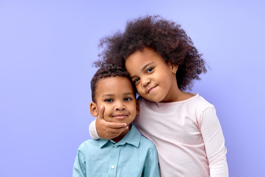 Photo of two young little black kids happy positive smile embrace family together isolated over violet purple color background. beautiful cildren in casual outfit love each other, hugging