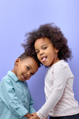 happy black children posing at camera and cheerfully smiling over purple background, cute american brother and sister having fun together, showing tongue, wearing casual clothes. familt, children