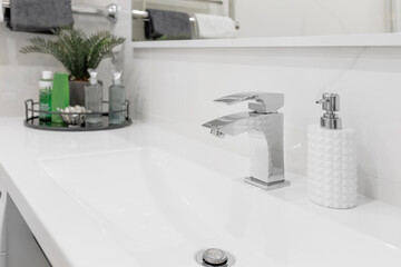 Water faucet mixer located in a modern, bright bathroom. Close-up