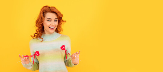 Obraz na płótnie Canvas Woman isolated face portrait, banner with copy space. happy cheerful redhead girl with red heart sticks on yellow background. february 14.