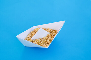 decorative paper ship origami with wheat on a blue background.. - 560819345
