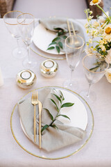 Banquet table decorated with plates, cutlery, candles, glasses and flower arrangements