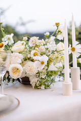 Banquet table decorated with plates, cutlery, candles, glasses and flower arrangements