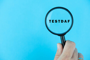 Focused on TestDaF exam. Word TestDaF (Deutsch als Fremdsprache) under magnifying glass. German or Dutch Language Proficiency Test. Test Preparation. E-learning.