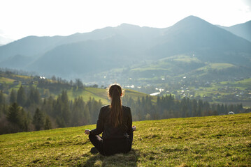 Naklejka na ściany i meble Young woman meditating outdoors in mountains 