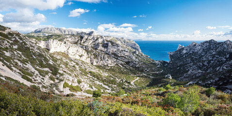A panoramic view to a rocks and a road leading through a valley to a turquoise sea