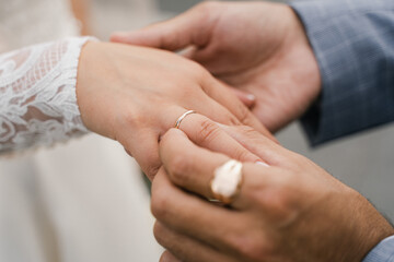 groom puts wedding ring on bride