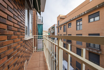 Narrow balcony terrace of a house with metal railing and green folding awning