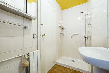 Bathroom in white tones with shower without screen and white aluminum radiator