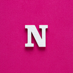 Alphabet letter N - White wooden letter on rhodamine red background