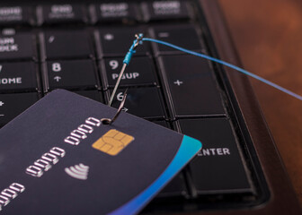 soft focus. close-up. bank card. the keyboard is black. a fishing hook. concept. stealing money on...