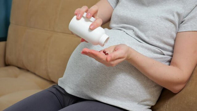 Pregnant woman takes care of future baby in bump and own health and uses pills. Gravid lady takes vitamins in pills to be wellbeing and have healthy baby