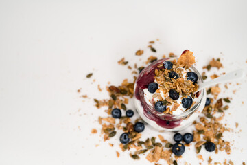 Healthy Snack Lifestyle Image. Yogurt parfait with granola, blueberry preserves and fresh blueberries. Top down view of parfait with negative space to left.