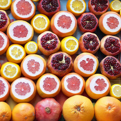 cut fresh oranges, pomegranates, grapefruits and lemons close up for fruity background