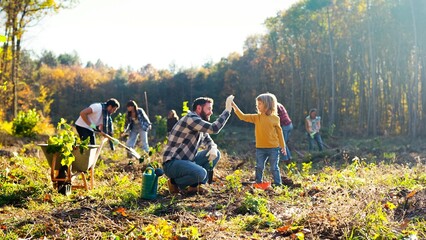 Little Caucasian cute boy helping her father to plant tree in forest or garden on sunny fall day....