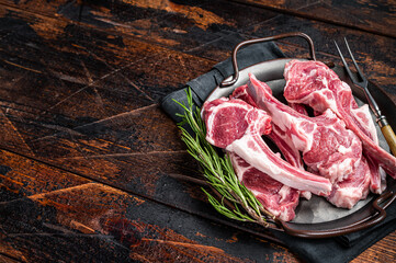 Raw lamb mutton chop steaks, fresh meat cutlets on butcher table. Black background. Top view. Copy...