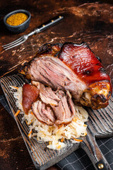 Schweinshaxe Roasted Pork Ham Hock, knuckle with Sauerkraut served on a wooden board. Dark background. Top view