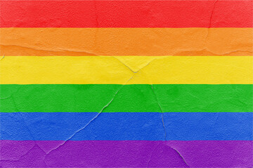 Pride rainbow flag painted on cracked textured wall. Outdoor Grunge texture background