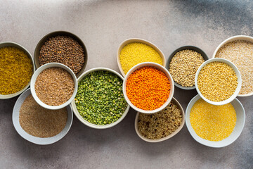 Various grain cereals in bowls on a light background, top view