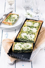 Traditional French tart with buffalo mozzarella and leaf spinach served as close-up in a backing form