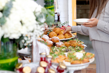 Woman choosing different snacks at a table. Table with a variety of trays containing different types of snacks