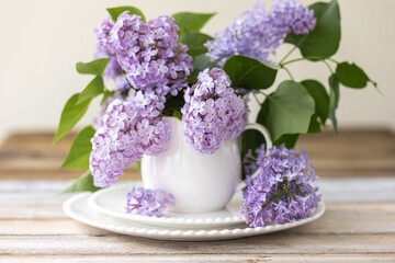 Obraz na płótnie Canvas Beautiful spring composition with lilac flowers in a white cup for countryside decor. Greeting postcard for Women's day, Mother's Day, 8th of March. Birthday anniversary present