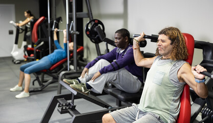 Fototapeta na wymiar Caucasian man training on shoulder press machine in gym
