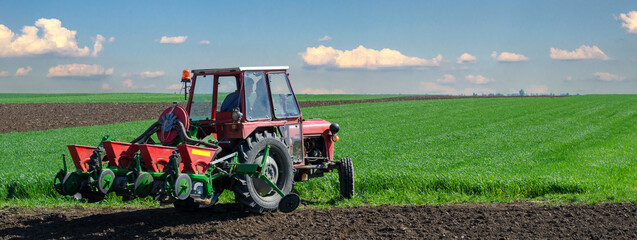 Farmer with tractor sowing on agricultural fields on a sunny spring day © Solid photos