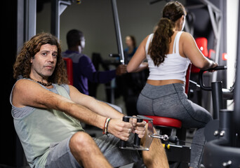 Fototapeta na wymiar Caucasian man using cable row machine in gym