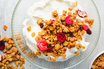 Granola with Yogurt in a Boal, Healthy Breakfast, Muesli with Dried Berries on Bright Concrete Background