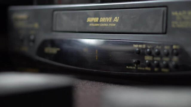 A man inserts a video cassette into a VCR