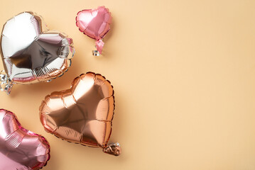 Valentine's Day concept. Top view photo of glossy heart shaped balloons on isolated pastel beige...