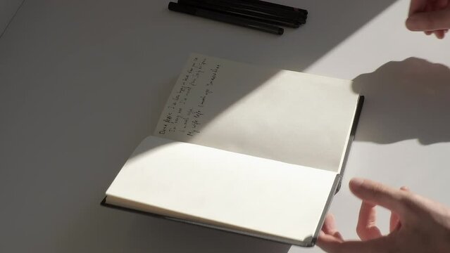 Close-up: Male hands stop writing text on a page and close the diary