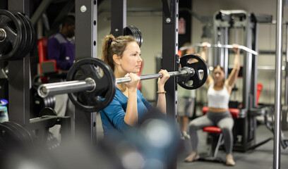 Athletic woman doing barbell exercises in the gym