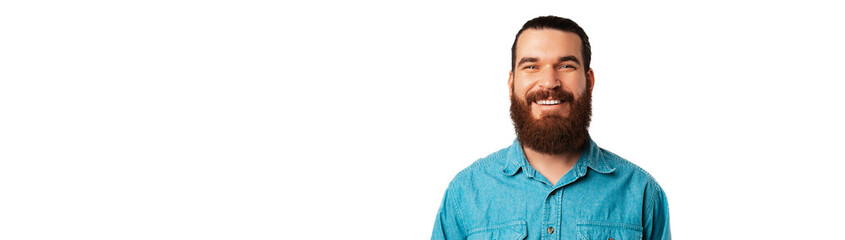 Obraz premium Banner shot of a wide smiling young bearded man wearing blue jeans shirt.