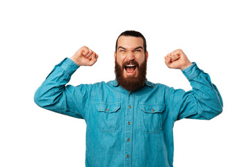 Powerful bearded man is making the winner gesture over white background.