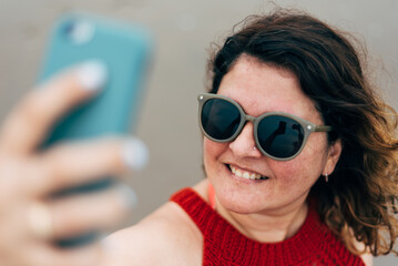 close-up of a woman taking a happy selfie with sunglasses