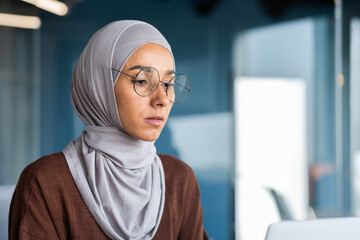 Close up of thinking business woman in hijab in modern office, serious muslim woman looking at...