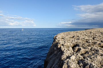 View over the ocean from a cliff as a boat sails in the distance