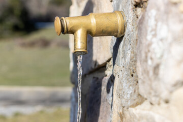 Classic open water faucet on a stone wall. Open vintage water faucet on a stone wall. water saving concept