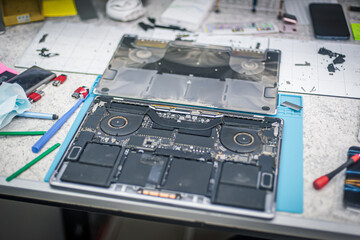 Fototapeta premium Technical support and fixing gadgets problems. Servicing, repairing, cleaning, maintaining computers. Repair shop. Hardware maintenance. Male technicians fixing disassembled laptop parts.