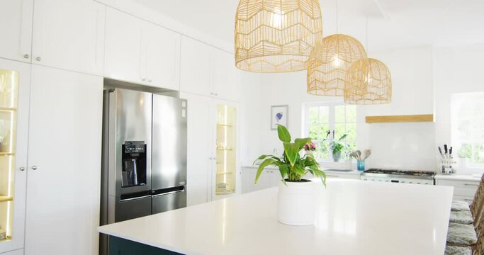 Video of modern, domestic kitchen with fridge freezer, hanging lamps over central island, copy space