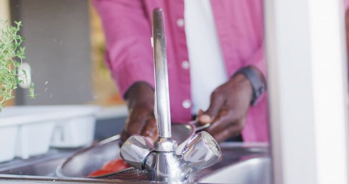Mid section of senior african american man spending time in log cabin, cooking in kitchen