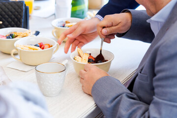 Man eating a dessert fruits bowl with many dessert bowls on a table. Close up of an elegant meal.