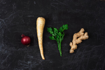 Red onion, parsnip root, ginger and parsley on black textured background. Minimal composition. Top view, flat lay - obrazy, fototapety, plakaty