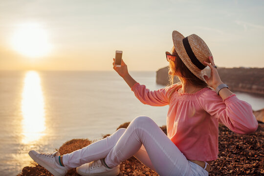 Tourist taking selfie on phone on Aegean sea background on Santorini island, Greece. Woman takes pictures traveling